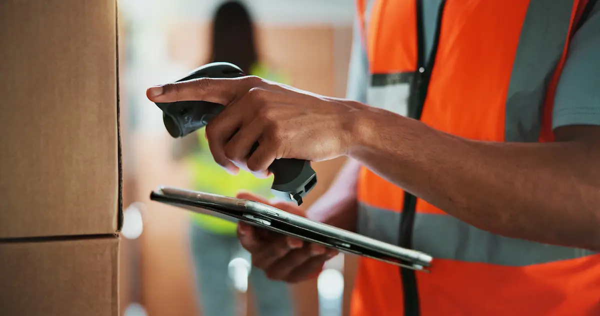 Depicts a store employee using mobile technology for inventory tracking, showcasing the practical application of IoT sensors and real-time data management.